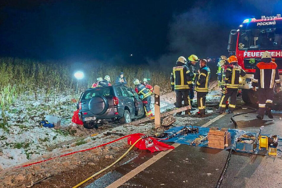 Feuerwehrleute stehen am Unfallort in Niederbayern neben dem Autowrack.
