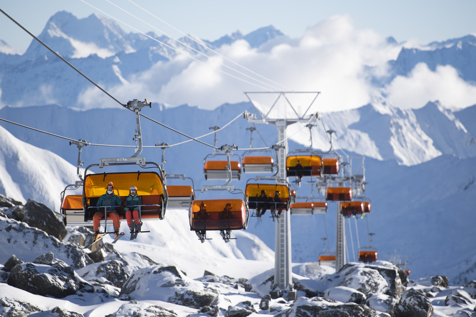 Schweiz, Samnaun: Skifahrer mit FFP2-Schutzmaske fahren mit einem Sessellift zum Viderjoch im Skigebiet Silvretta Arena in Samnaun.