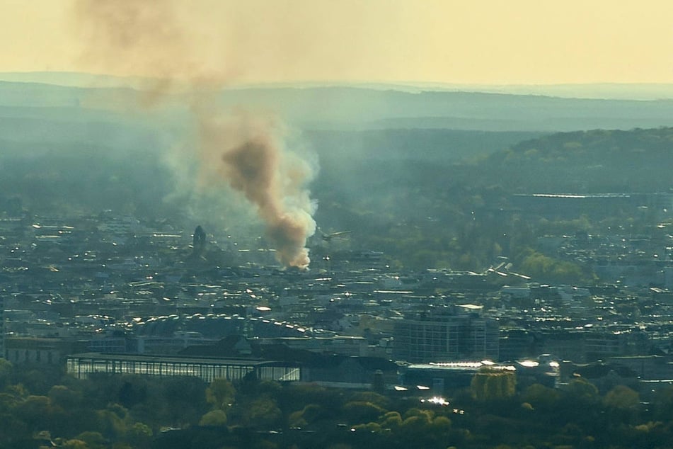 Eine große Rauchwolke steigt vom Brandort über dem Stadtgebiet auf.