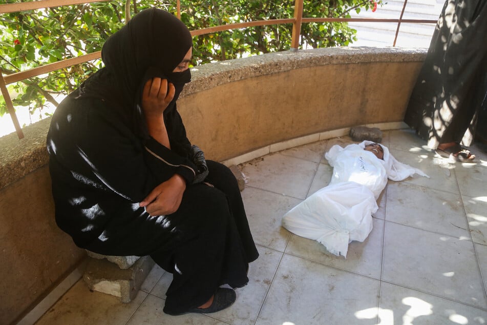 The mother of Palestinian youth Abdul Jawad al-Ghalban, who died of starvation, mourns by his shrouded body at Nasser hospital in Khan Younis on July 22, 2025.