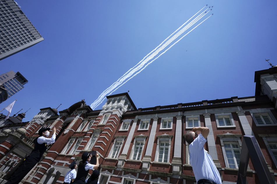 Personal beobachtet die Kunstflugstaffel der japanischen Selbstverteidigungsstreitkräfte, die mit einer kleinen Showeinlage über Tokio fliegt, um sich bei dem medizinischen Personal für seinen Einsatz während der Corona-Pandemie zu bedanken.