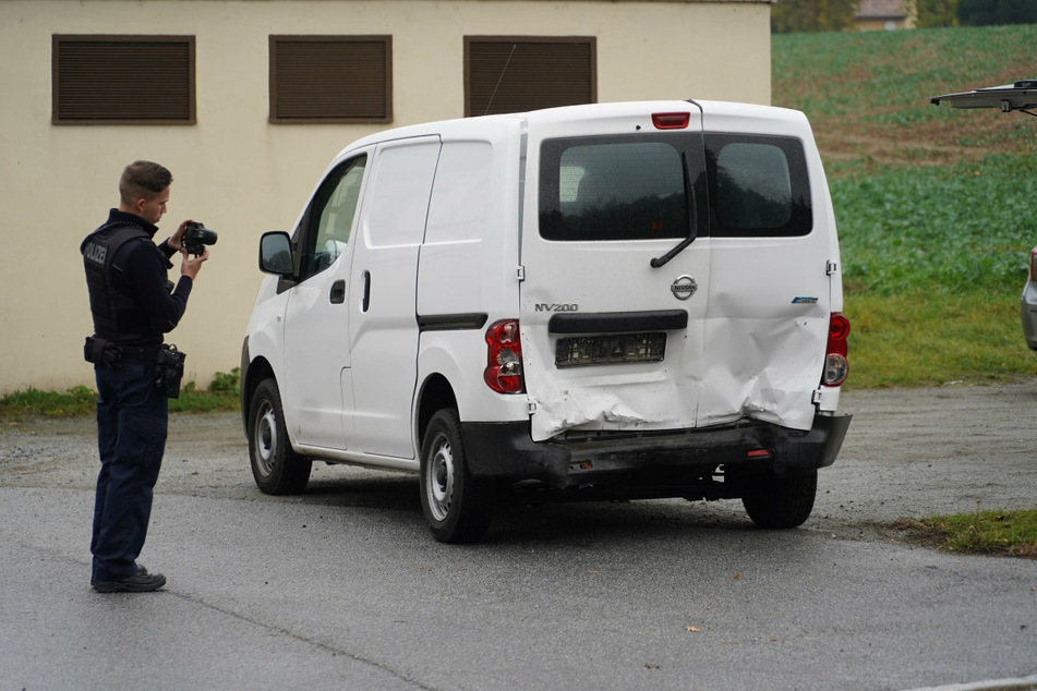 Ein Polizist fotografiert die Unfallschäden an dem Nissan.