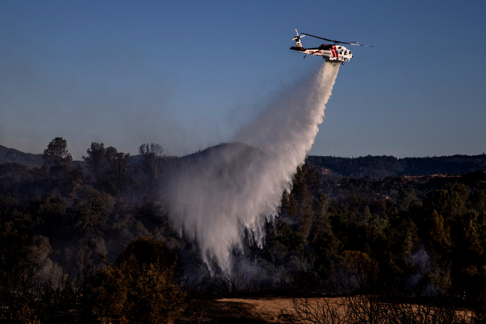 Ein "Cal Fire Sikorsky S70i Firehawk"-Hubschrauber wirft Wasser auf heiße Stellen in Clearlake.