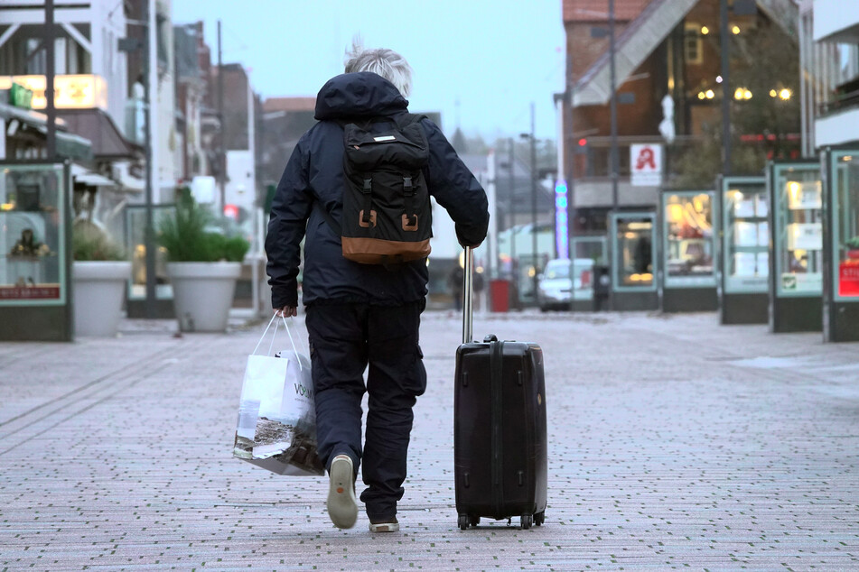 Ein Besucher geht Sylt mit einem Rollkoffer durch eine Füßgängerzone.