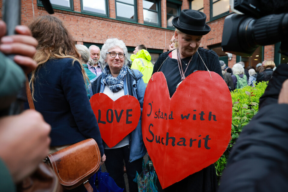 Zwei Anhängerinnen des prominenten Mediziners stehen mit roten Pappherzen und der Aufschrift "Love" und "I stand with Sucharit" vor Prozessbeginn vor dem Gerichtsgebäude.
