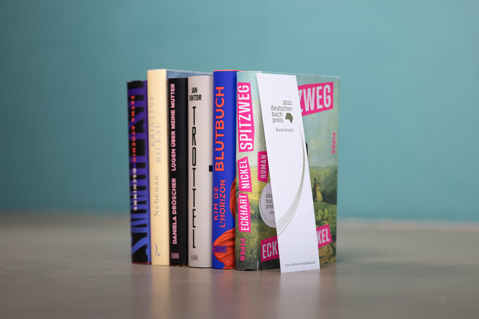 Die sechs Bücher der Shortlist für den Deutschen Buchpreis 2022 (v.l.n.r.): Fatma Aydemir (36, "Dschinns"), Kristine Bilkau (48, "Nebenan"), Daniela Dröscher (45, "Lügen über meine Mutter"), Jan Faktor (70, "Trottel"), Kim de l'Horizon ("Blutbuch") und Eckhart Nickel (56, "Spitzweg").