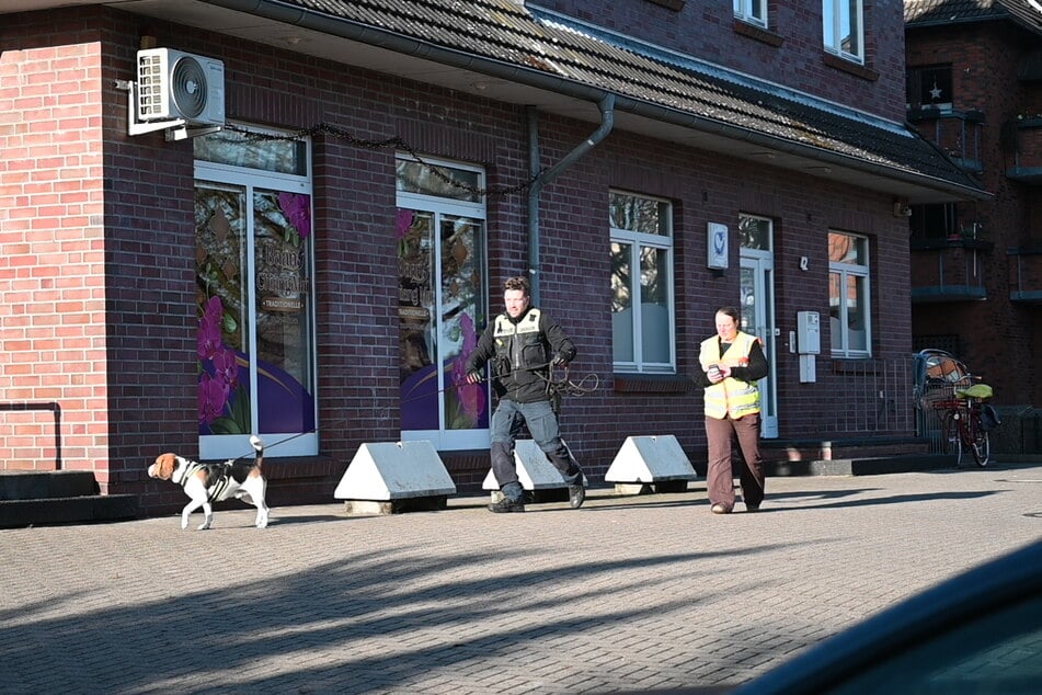 Zwei Beamten gehen mit einem Diensthund den mutmaßlichen Weg des Opfers ab.