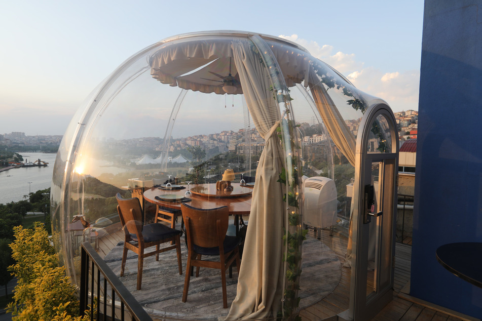 Tische in einem Außenbereich eines Restaurants sind als Maßnahme gegen die Ansteckung der Gäste mit dem Coronavirus mit durchsichtigem Plexiglas in Form von Kuppeln überspannt.