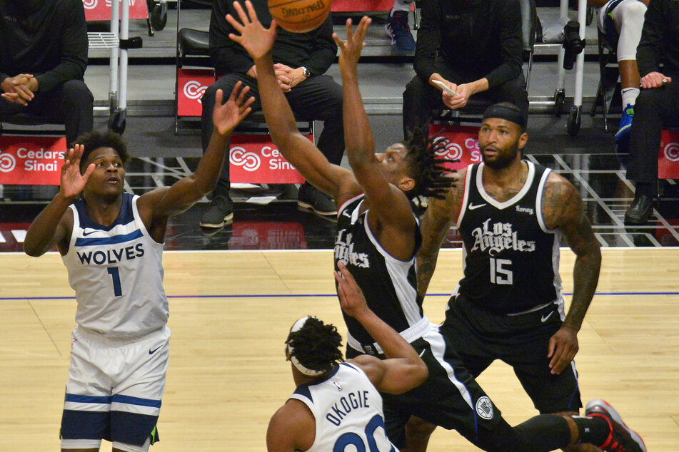 Los Angeles Clippers guard Terance Mann reaches for the rebound over Minnesota Timberwolves forwards Anthony Edwards and Josh Okogie.