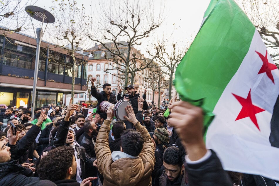 Exil-Syrer feiern auf dem Schillerplatz und der Ludwigstraße den Sturz des Assad-Regime und schwenken dabei die syrische Nationalflagge.