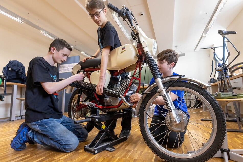 Max Erler (13, v.l.), Emil Säuberlich (14) und Yannik Schreyer (14) montieren den Auspuff ans Moped, das nach Fertigstellung einen Wert von circa 4500 Euro besitzen wird.