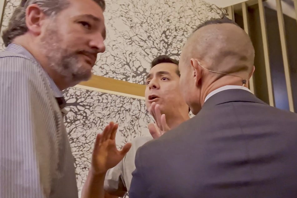 An activist named Benjamin Hernandez (c.) confronts Sen. Ted Cruz (l.) at Uptown Sushi in Houston.