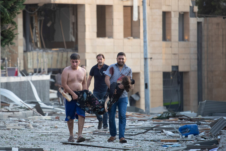 Menschen tragen eine verwundete Frau nach massiven Explosionen in Beirut. Die Explosionen erschütterten die Innenstadt von Beirut und beschädigten Gebäude. Es sollen Hunderte Menschen verletzt worden sein.