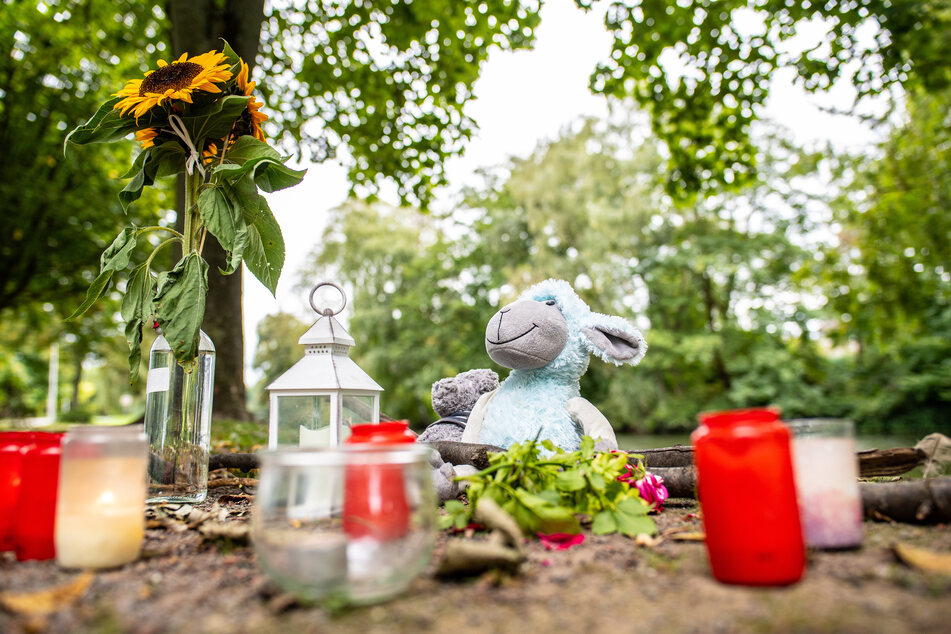 Zwei Stofftiere, Kerzen und Sonnenblumen stehen an dem kleinen See am Oberlandesgericht, wo am Sonntag die Frauenleiche gefunden wurde.