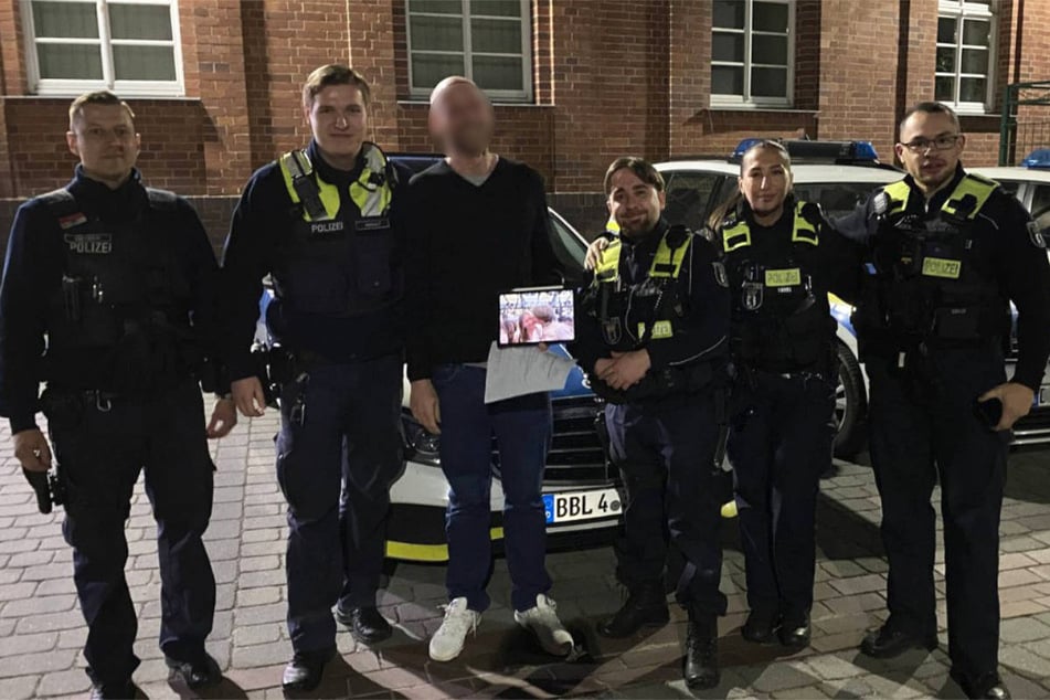 Der Vater posiert freudestrahlend mit dem gefundenen Tablet und den beteiligten Beamten.