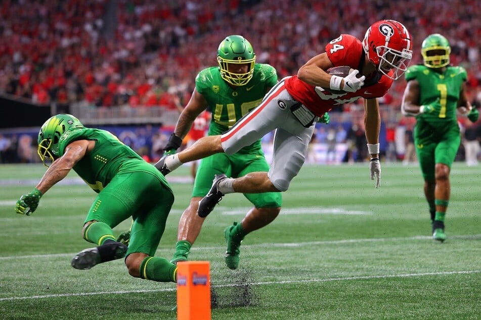 Ladd McConkey of the Georgia Bulldogs leaps over Bennett Williams of the Oregon Ducks to score a touchdown in their season opener matchup.