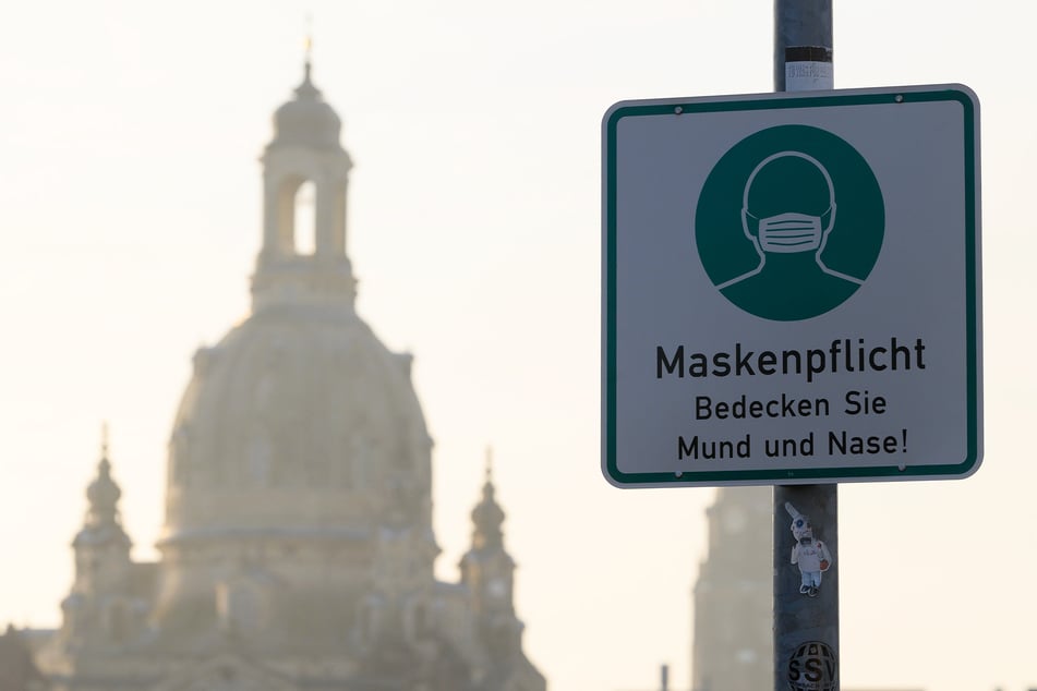 Ein Hinweisschild auf die Maskenpflicht hängt vor der Frauenkirche an einem Lampenmast.