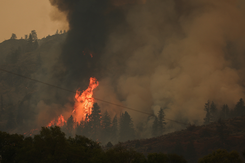 Wildfires have stretched into Washington, causing thousands to flee and killing at least one person.