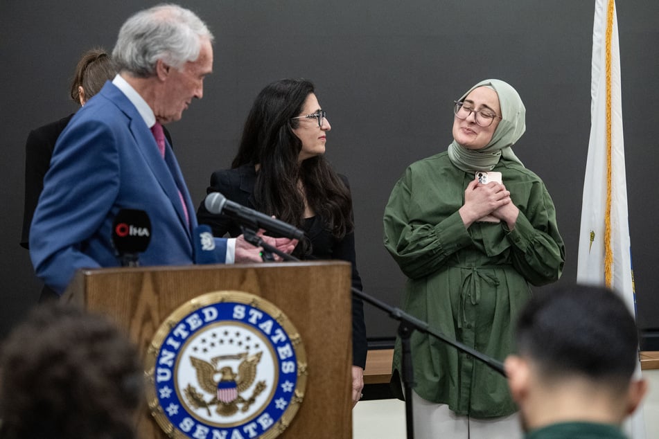 Rümeysa Öztürk (r.) reacts as Senator Ed Markey (l.) speaks during a press conference at Logan International Airport in Boston, Massachusetts, on May 10, 2025.