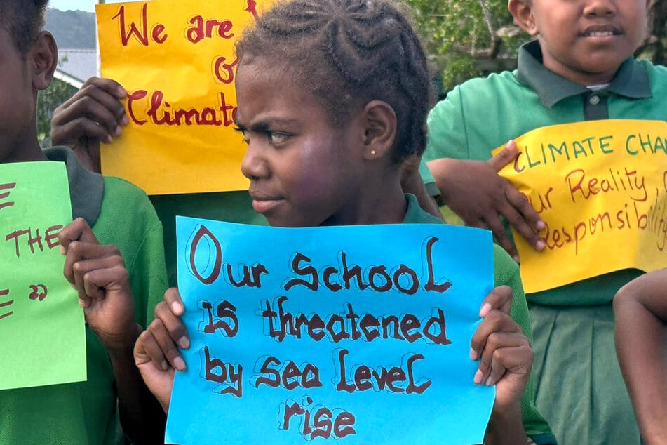 Schoolchildren from the Suango Mele primary and secondary school, located in the village of Mele, north of the Vanuatu capital of Port Vila, hold signs calling out the impacts of climate change on July 24, 2025.