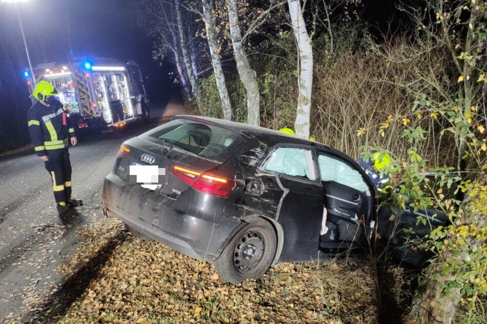 Ein Feuerwehrmann blickt auf den kaputten Audi.
