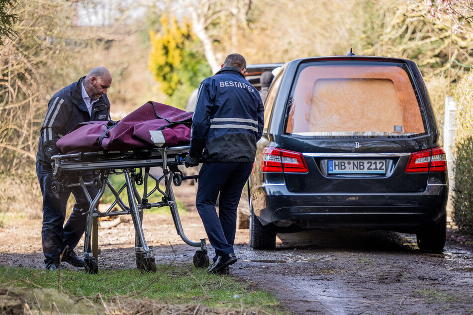 Zwei Bestatter rollen eine Leiche aus der Parzelle des Kleingartens. Insgesamt kamen drei Menschen bei dem Brand in Bremen ums Leben.