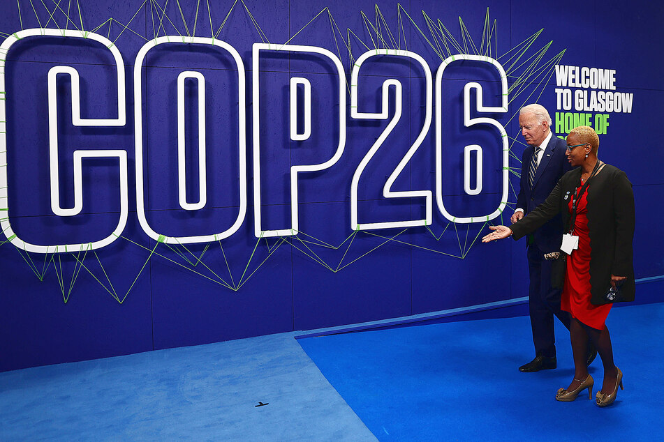 President Joe Biden directed by COP26 staff at the COP26 photo op sign.