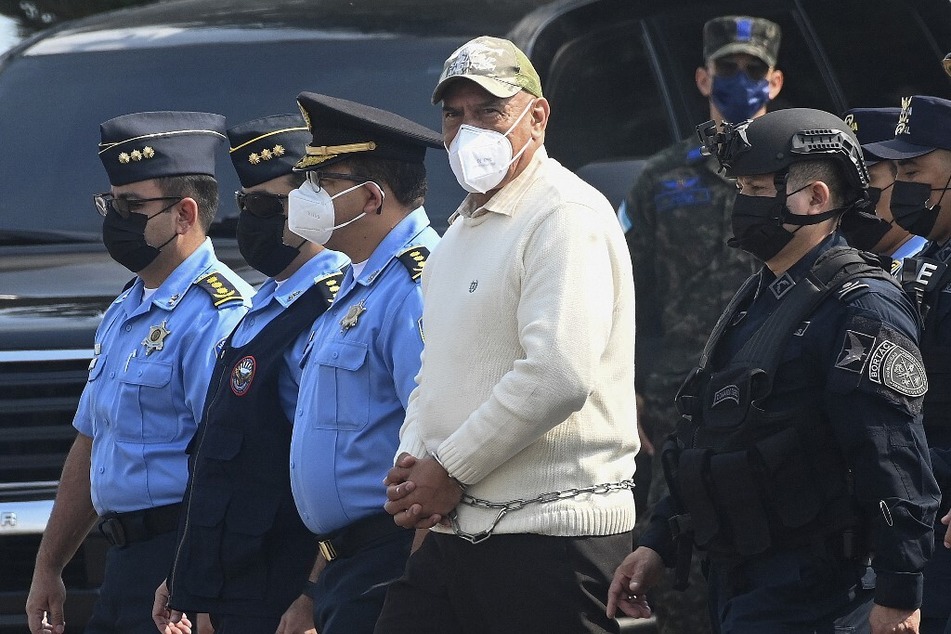 National police and special forces officers escort the former chief of the Honduran police, Juan Carlos Bonilla, as he walks towards a plane at an Air Force base to be extradited to the US.