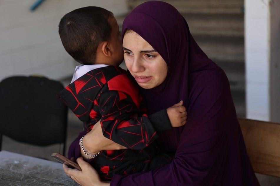 A displaced Palestinian woman holds a child inside UN school-turned-refuge in the Al-Shati refugee camp near Gaza City in the northern Gaza Strip, following a reported Israeli strike on October 19, 2024.