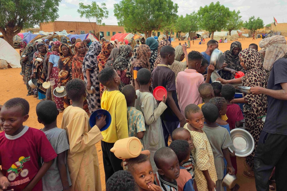 Displaced people line up to receive food being distributed in al-Mohayra camp near the city of El-Obeid in the southern Kordofan region on June 29, 2026.