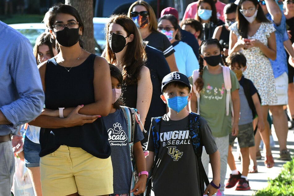 Students wearing face masks arrive with their parents on the first day of classes for the 2021-22 school year at Baldwin Park Elementary School in Orlando, Florida.