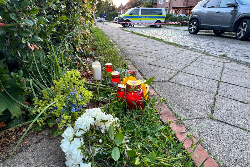 Vor der Absperrung haben Menschen am Dienstag zum Gedenken an die sechs Opfer Blumen gelegt und Kerzen angezündet.
