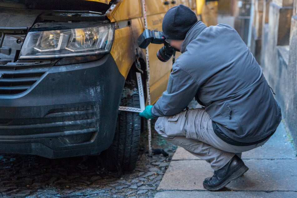 Am Morgen danach untersucht ein Kriminalist den angezündeten Post-Transporter.