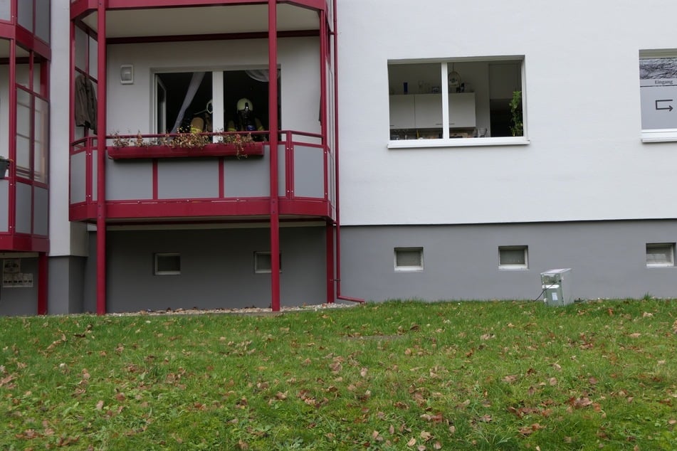 Feuerwehrkameraden in der betroffenen Wohnung. Vor dem Küchenfenster liegt eine Mikrowelle auf der Wiese.