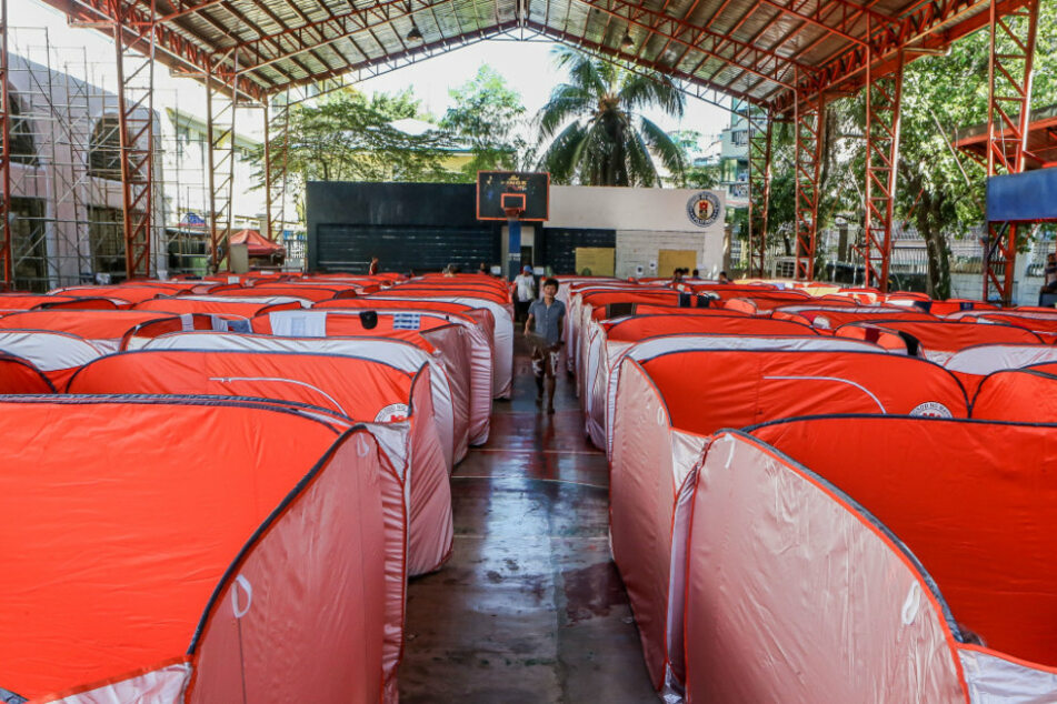 Philippinen, Manila: Ein Mann geht zwischen modularen Zelten, welche für Straßenbewohner auf einem Basketballplatz aufgestellt wurden, um die weitere Verbreitung von Covid-19 zu verhindern.