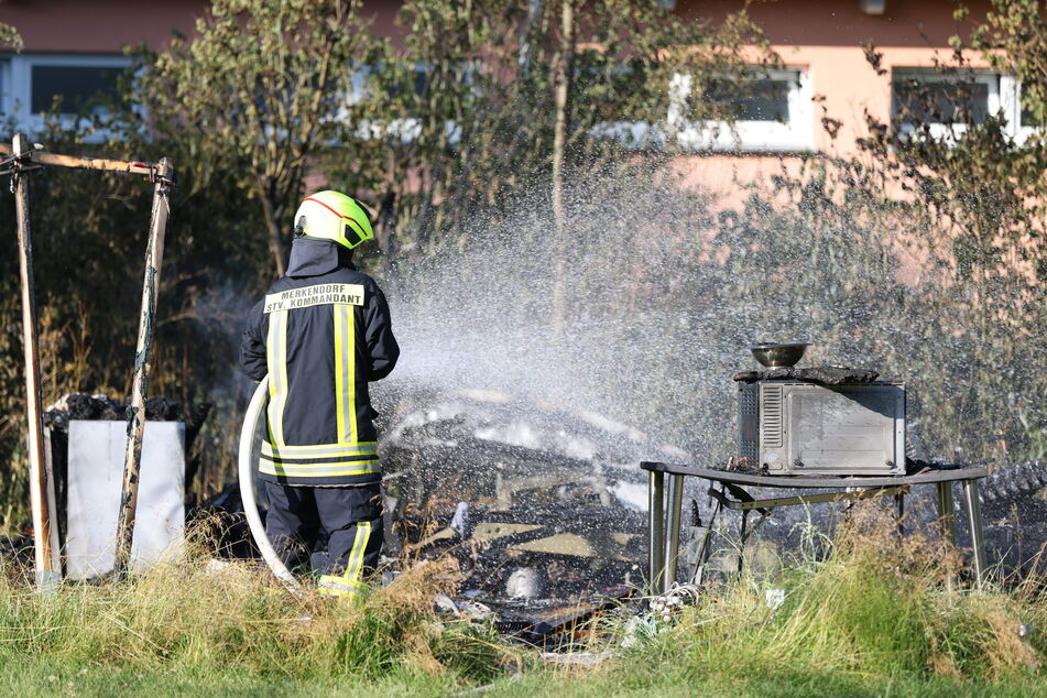 Ein Feuerwehrmann löscht die schwelenden Überreste des Wohnmobils.