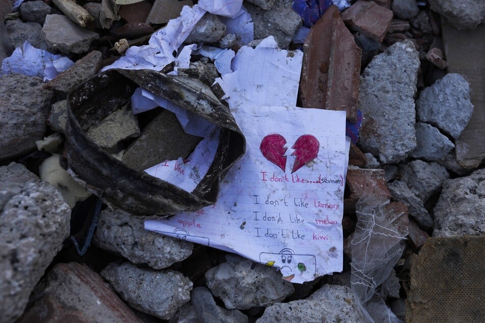 Ein Blatt Papier liegt inmitten der Trümmer eines zerstörten Gebäudes. Unter den Tausenden eingestürzten Gebäuden im türkisch-syrischen Grenzgebiet sind vermutlich noch Zehntausende Erdbebenopfer zu befürchten.