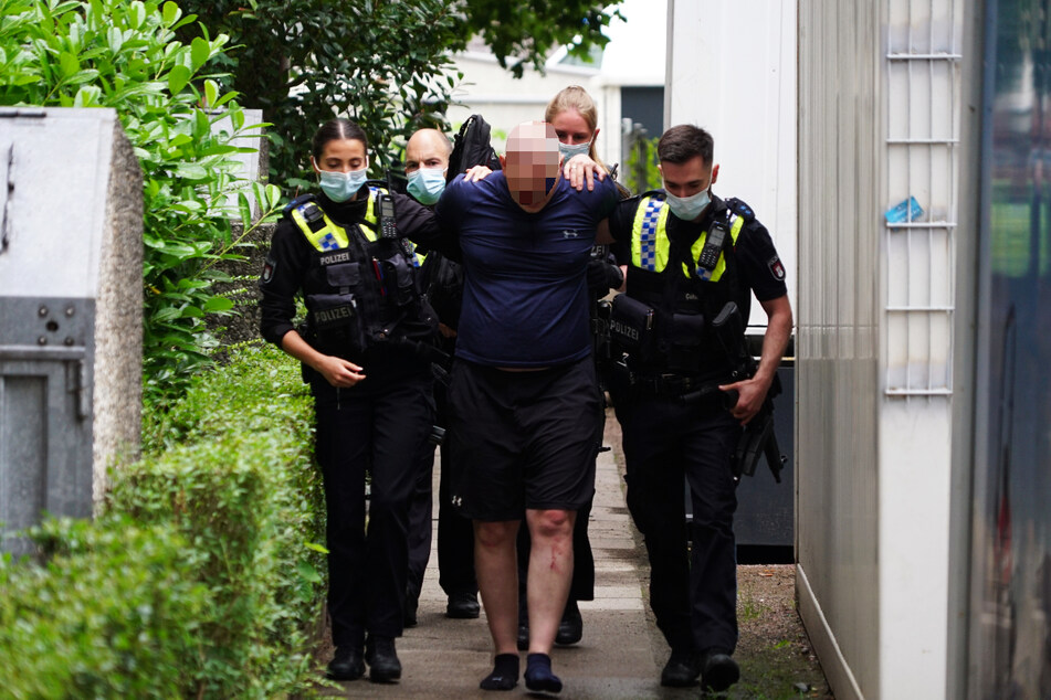 Der 46-Jährige wird von Polizeibeamten abgeführt. Er hatte eine Taxifahrt nicht bezahlt, sich in seiner Wohnung verbarrikadiert und einen SEK-Einsatz ausgelöst.