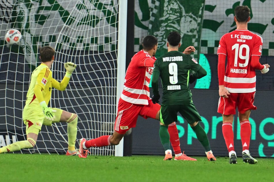 Mohamed Amoura (2.v.r.) lässt Frederik Rönnow (l.) mit seinem satten Rechtsschuss keine Chance und erhöht auf 2:0 für Wolfsburg.