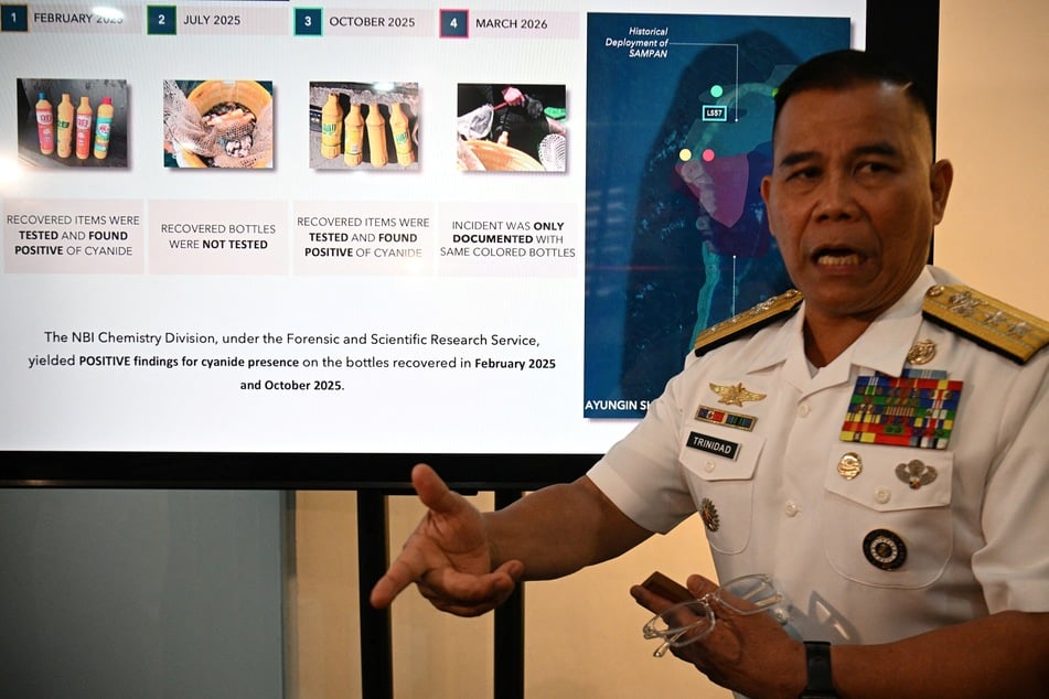 Philippine Navy spokesperson Rear Admiral Roy Vincent Trinidad speaks next to a slide presentation of seized yellow bottles suspected to contain cyanide in the waters of Second Thomas Shoal in the South China Sea, during a press conference in Manila on April 13, 2026.