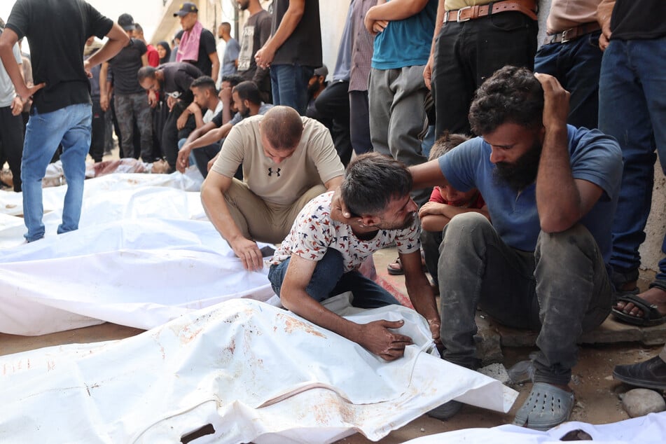 Palestinians mourn relatives killed in Israeli strikes ahead of their funeral at Al-Shifa hospital in Gaza City on August 21, 2025.