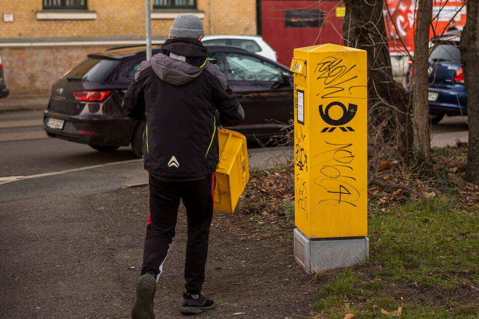 Ein Post-Fahrer leert in Leipzig einen Briefkasten aus. Auf dem Weg ins Verteilzentrum soll der Angeklagte Briefe herausgefischt und nach Geld durchsucht haben. (Symbolbild)