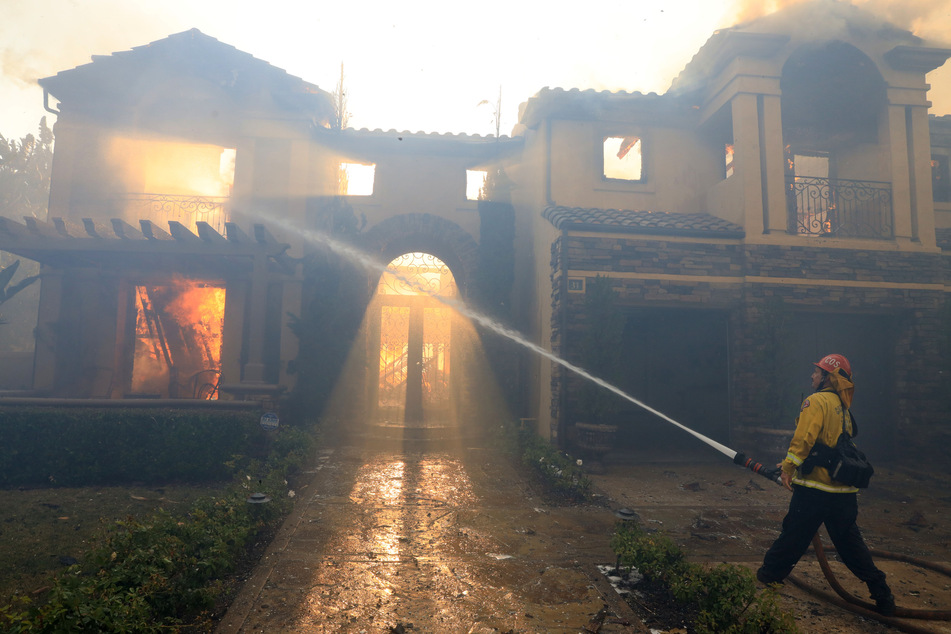 Feuerwehrmann Nick Cerciello vom Costa Mesa Fire Department gibt sein Bestes beim Versuch, ein brennendes Haus zu löschen.