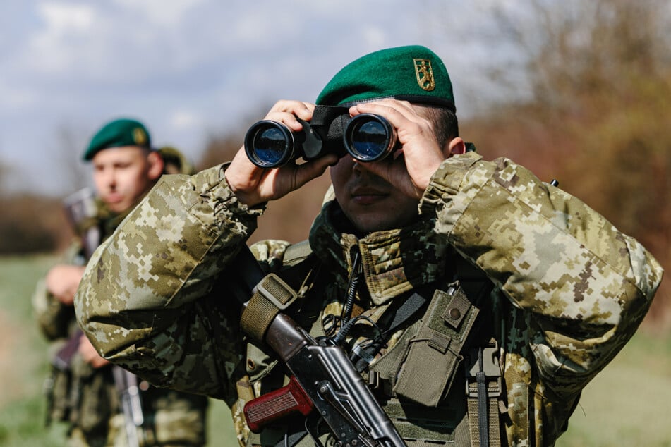 Ein Soldat der ukrainischen Grenzschutzeinheit Kosyno sucht mit einem Fernglas die Umgebung ab.