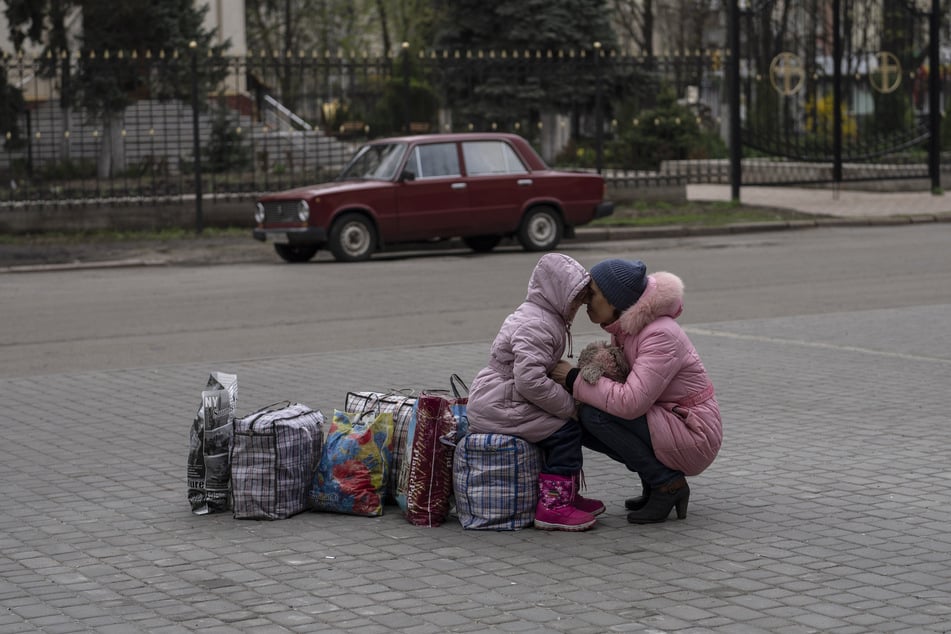 Eine Mutter umarmt ihre Tochter, während sie auf einen Bus warten, um aus der Stadt Slowjansk im Bezirk Donezk zu fliehen.