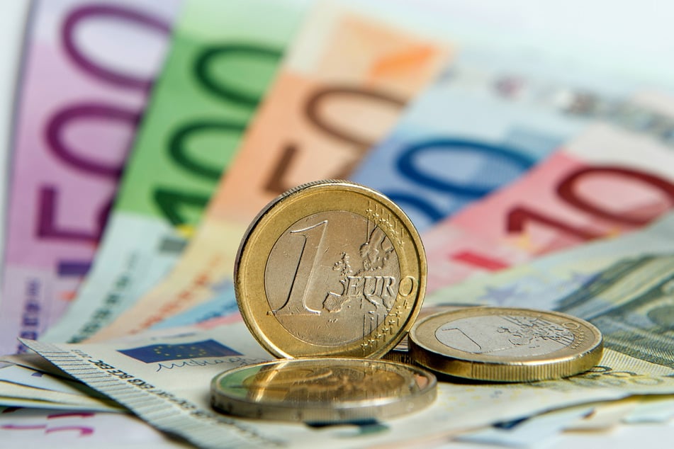 Euro-Banknoten und Euromünzen liegen auf einem Tisch. Gutverdiener sind einer Studie zufolge mit der Krisenpolitik im Schnitt zufriedener als solche mit weniger Einkommen.