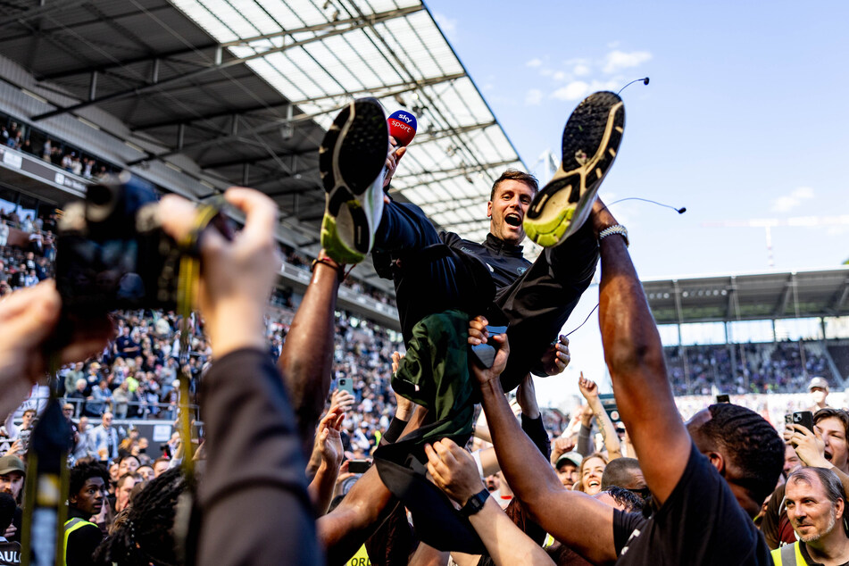 Die Fans feiern FCSP-Cheftrainer Fabian Hürzeler (31) und werfen ihn während der Aufstiegsfeier auf dem Platz in die Luft.