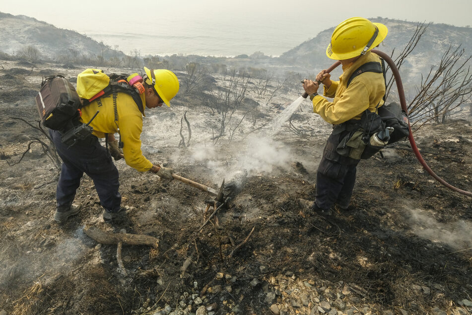Feuerwehrleute des County of Santa Barbara Fire Departement löschen einen Brand am Straßenrand des Highways 101.