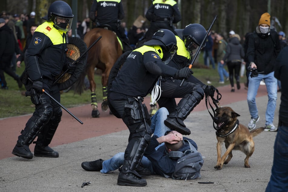 Ein niederländischer Bereitschaftspolizist tritt einen am Boden liegenden Mann während einer Demonstration gegen die Corona-Maßnahmen.