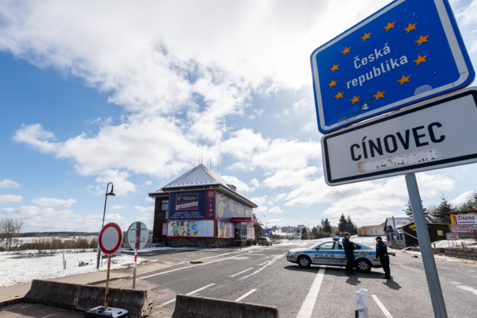 Tschechische Polizisten stehen zur Einreisekontrolle auf einer Straße an der Grenze in Cinovec.